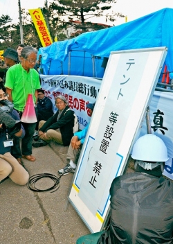 座り込みの市民らのテントの前に「設置禁止」の看板を立てる沖縄総合事務局の作業員＝２６日午後６時２３分、名護市辺野古