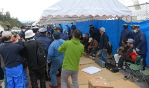 三線演奏の雨よけのために建てられたテントの足を持ち上げ、撤去する機動隊員ら＝４日午前９時２３分、名護市辺野古の米軍キャンプ・シュワブゲート前