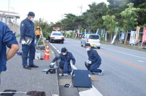 事故現場で鑑識作業する県警職員=24日午前8時40分ごろ、米軍キャンプ・シュワブゲート前
