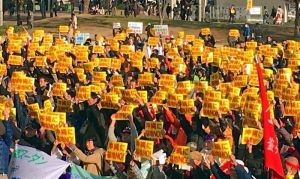 「沖縄に基地NO!」の黄色いプラカードを掲げる参加者=日、大阪市・扇町公園