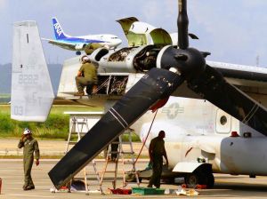 民間機が離着陸する中、オスプレイの右翼のパネルを開けてエンジン部分を点検する米軍関係者ら=30日午前10時20分ごろ、石垣市白保・南ぬ島石垣空港(新垣玲央撮影)