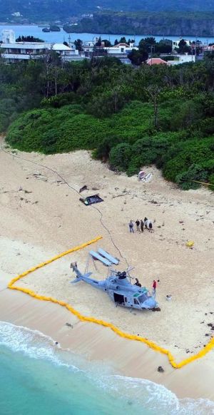ローターが全て取り外された米軍UH1ヘリ(手前)。不時着現場から約50メートルの距離に住宅地がある=7日午前11時すぎ、うるま市・伊計島(小型無人機から)