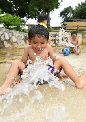 強い日差しの中、公園の噴水で遊ぶ子どもたち=7日午後、金武町・大川児童公園(喜屋武綾菜撮影)