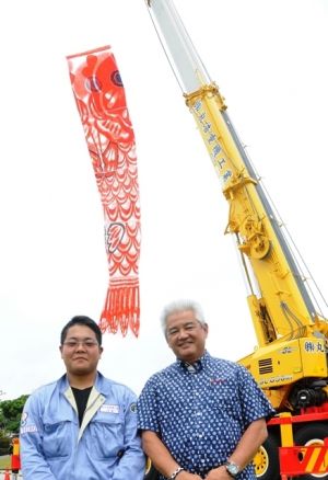 掲揚に協力する丸浩重機工業の比嘉俊浩社長(右)とオペレーターの宮城涼さん=3日、糸満市摩文仁