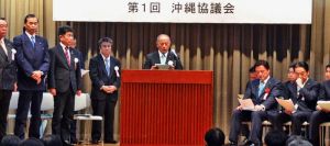 沖縄の基地負担軽減を全国で考える活動に向けた決議を読み上げる山口県岩国市議会の桑原敏幸議長(中央)=3日、那覇市・青年会館