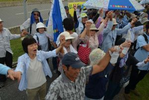 辺野古新基地建設に対し、手をつないで反対の声を上げる集会参加者=7日午後0時40分、名護市辺野古