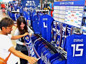 サッカー日本代表の応援グッズを品定めするサポーター=25日、豊見城市のスポーツデポ豊崎店