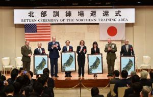 セレモニーで米軍側から返還写真のパネルを贈呈された宮城久和国頭村長(左から2人目)、伊集盛久東村長(右)と日米関係者=22日、名護市・万国津梁館