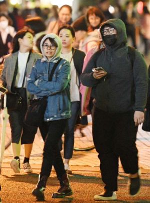 厚着姿で交差点を歩く人たち=9日午後6時半ごろ、那覇市久茂地(田嶋正雄撮影)