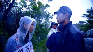 「標的の島 風かたか」のワンシーン。雨が降りしきる中、機動隊員と女性の視線が交錯する
