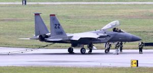 オイル漏れのため緊急着陸したF15戦闘機。滑走路上にもれたオイルを拭き取って袋に詰めて移動する消防隊員ら=19日午前10時前、嘉手納基地(読者提供)