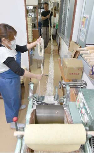 1本5メートルに切った麺をまとめる三竹寿製麺所の職員=30日、浦添市経塚