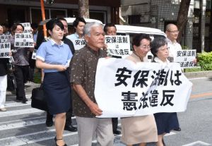 安全保障関連法の違憲性を訴え、那覇地裁に入る原告と代理人弁護士=23日午前10時ごろ、那覇市樋川