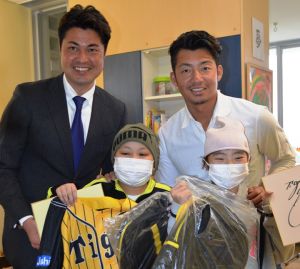 子どもたちを激励する鳥谷敬選手(後列右)と比嘉寿光さん(同左)=5日、南風原町の県立南部医療センター・こども医療センター