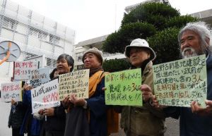 山城博治議長らの釈放を求め、那覇地裁前でプラカードを掲げる支援者ら=10日、那覇市樋川