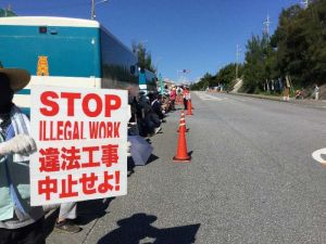 「違法工事中止」のプラカードを掲げ新基地建設反対を訴える市民=15日午前8時半、名護市辺野古
