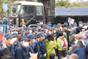 機動隊に守られてダンプがヘリパッド建設予定地に砂利を搬入した=28日午後1時すぎ、国頭・東村境