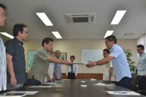 沖縄防衛局の中嶋局長(右)に抗議文を手渡す三連協の会長を務める桑江沖縄市長=12日午前8時45分ごろ、沖縄防衛局
