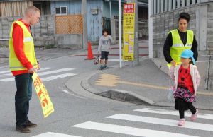 子どもたちの登校を見守り、交通安全のボランティアをする米兵有志=北谷町吉原・北玉小学校前