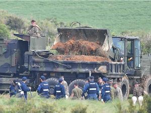 重機で土壌を掘り返し、トラックに運び込む米軍関係者=20日午後5時、東村高江