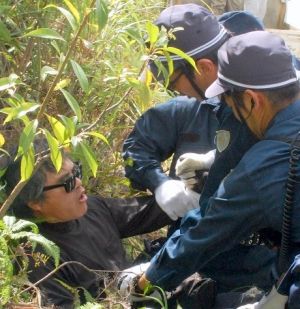 目取真俊さん(左端)を4人がかりで押さえ込む警察官=18日、東村高江・米軍北部訓練場N1地区表側出入り口