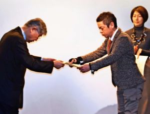 メディア・アンビシャス世話人の萩本和之さん(左)から表彰状を受け取る伊集竜太郎記者=4日、札幌市内