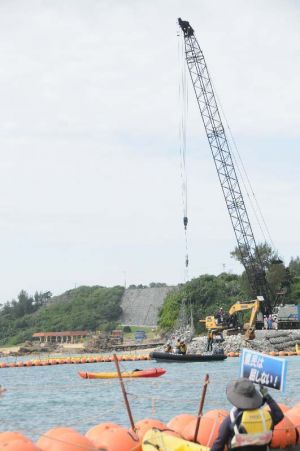 名護市辺野古の米軍キャンプ・シュワブ沿岸では、新基地建設に反対する市民がカヌー16艇で抗議する中、護岸の石積み作業が行われた=26日午前9時20分ごろ