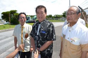 抗議後、記者談の質問に答える三連協会長の桑江朝千夫沖縄市長(中央)=23日午前10時40分ごろ、米軍嘉手納基地第1ゲート前