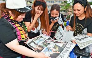 配布された号外に見入る安室奈美恵さんのファン=23日午後6時52分、那覇市久茂地(金城健太撮影)