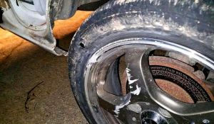 作業員に側溝へ落とされ、穴が空きホイルにも傷が付いた左前輪(男性提供)