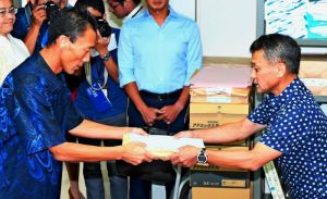 県水産課職員(右)に、サンゴの特別採捕許可に関する書類を手渡す沖縄防衛局職員=26日午前、県庁