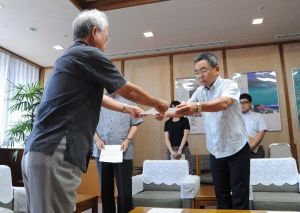 沖縄防衛局の中嶋浩一郎局長(右)へ抗議文を手渡す富川盛武副知事=7日、県庁