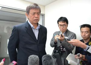 記者団の取材に厳しい表情で答える謝花喜一郎知事公室長=21日午後0時38分、沖縄県庁