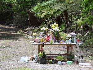 女性の遺体が遺棄された雑木林。献花台には多くの花が手向けられている=26日午後、恩納村安富祖
