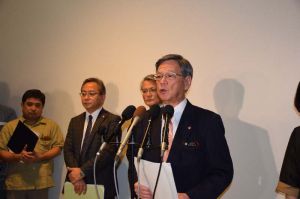 米軍普天間飛行場の返還合意から21年を迎え、「早期返還と危険性の除去を求めたい」と話す翁長雄志知事(中央)=12日午後、那覇空港国際線ターミナル