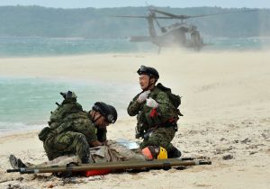 【資料写真】負傷した米兵を自衛隊員が救助する想定の演習。後方は米軍の救難ヘリ=2010年、うるま市・浮原島