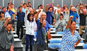 「日本軍の強制」明記を求め、ガンバロー三唱する参加者=29日、浦添市産業振興センター結の街