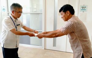 沖縄防衛局調達計画課の杉山英広課長(左)に、聴聞通知書を手交する県土木建築部の松島良成土木整備統括監=31日午後4時26分、嘉手納町嘉手納の沖縄防衛局