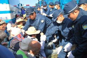 ゲート前に座り込む市民らを排除する県警機動隊員ら=24日午前8時45分、名護市辺野古・米軍キャンプ・シュワブのゲート前