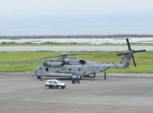 久米島空港に緊急着陸したCH53E大型輸送ヘリ。機体そばでは米兵が警察官に事情聴取されていた=1日午後2時20分ごろ、同空港(又吉嘉例撮影)