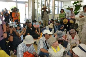 沖縄防衛局の玄関で座りこむ新基地建設に反対する市民ら=7日午前10時40分ごろ、嘉手納町・沖縄防衛局