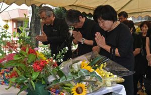 米軍戦闘機墜落事故から59年を迎え、慰霊祭で手を合わせる参加者=30日午前10時すぎ、うるま市立宮森小学校