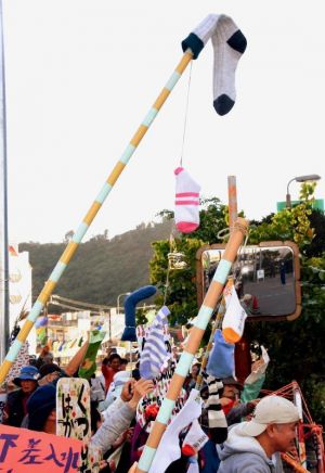 靴下を掲げて差し入れの許可を求める市民=10日、名護署前