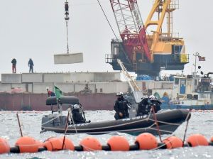 大型コンクリートブロックを台船から作業船へ積み替えるクレーン=6日午前11時10分、名護市辺野古沖