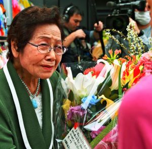 館長退任式で、涙ぐみながら関係者の花束を受け取る島袋淑子さん=30日、糸満市伊原・ひめゆり平和祈念資料館