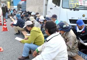 工事車両の進入を警戒し、米軍キャンプ・シュワブゲート前に座り込む人たち=8日午前7時32分、名護市辺野古