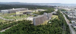 名護市辺野古にある国立沖縄工業高等専門学校。手前の建物が学生寮、左奥が校舎。右奥は米軍キャンプ・シュワブの施設=8日(小型無人機で撮影)
