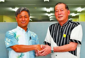 座談会で握手を交わす松川正則氏(右)と仲西春雅氏=14日、沖縄市・沖縄タイムス中部支社