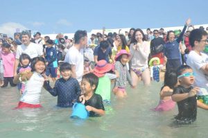 日本最南端の海開きで、一斉に海に入る参加者ら=18日午前10時半すぎ、竹富町小浜島・はいむるぶしビーチ
