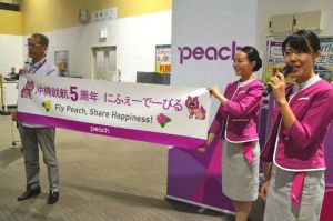 乗客に沖縄就航5周年の感謝を伝えるピーチのスタッフら=18日、那覇空港LCCターミナル